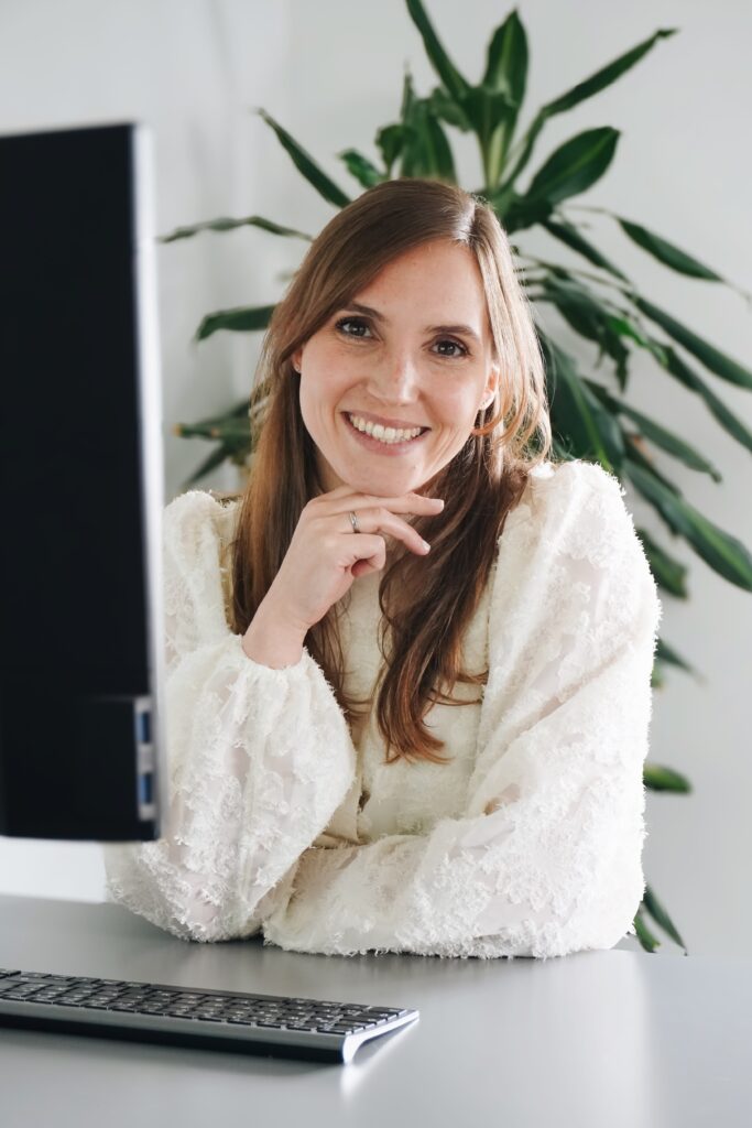 Die Gründerin Lisa Müller vor ihrem Bildschirm, in die Kamera lächelnd.