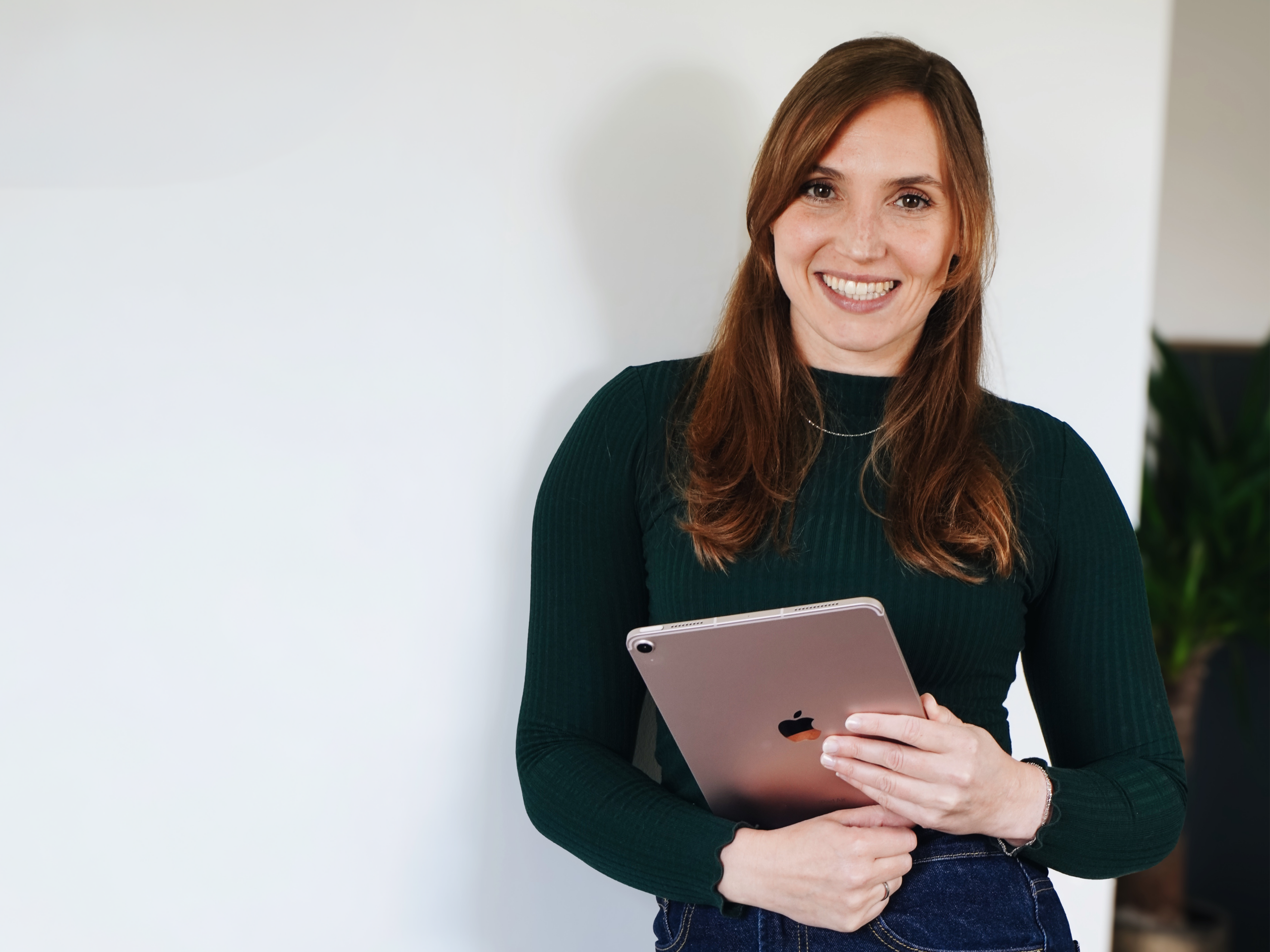 Die lächelnde Gründerin Lisa Müller in einem grünen Pullover mit dem Tablet in der Hand.
